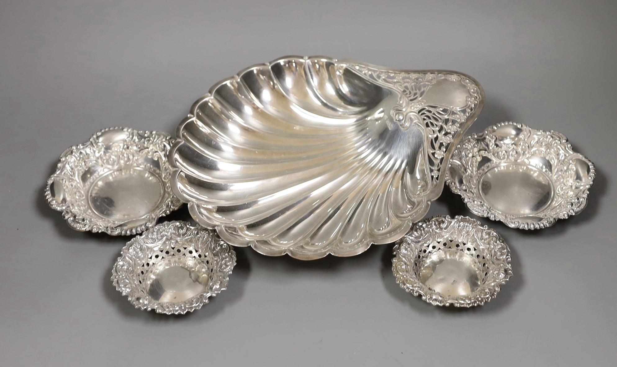 An Edwardian Art Nouveau silver shell dish, with pierced handle, on ball feet, Atkin Brothers, Sheffield, 1905, 28.3cm, together with two small pairs of repousse silver bonbon dishes, 16oz.
